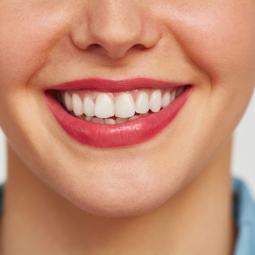 Close-up shot of female face with charming toothy smile against white background